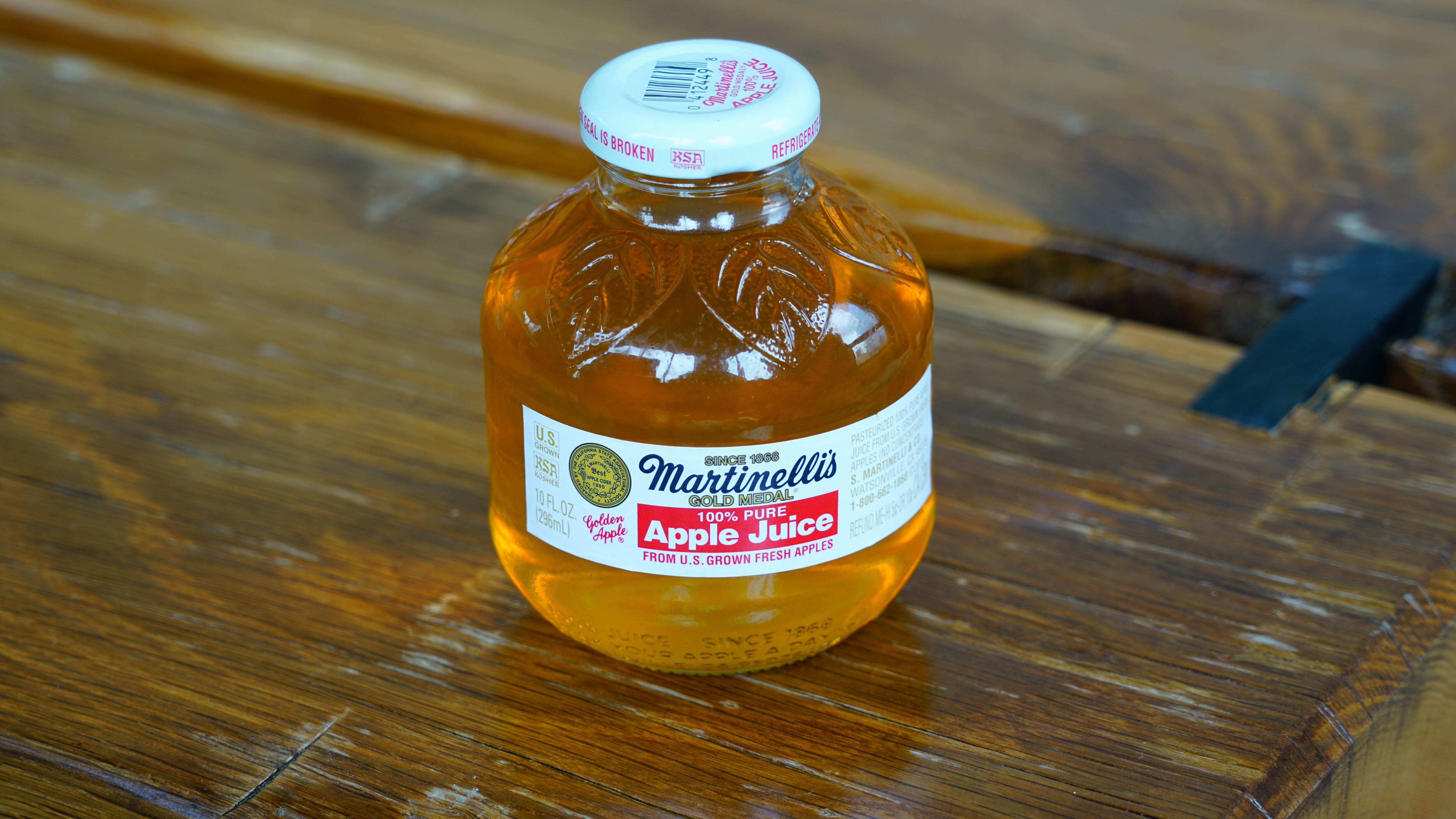 View of a small round glass bottle of Martinellis Gold Medal Apple Juice.