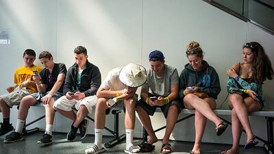 CLEVELAND, OHIO - JULY 3: Teens look at their iPhones July 3, 2015 at the Rock and Roll Hall of Fame in Cleveland, Ohio. (Photo by Robert Nickelsberg/Getty Images)