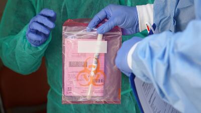 BERLIN, GERMANY - APRIL 08: Medical staff prepare to seal a bag containing a throat swab sample they took from a person seeking a test for possible Covid-19 infection at the garage that the medical practice they work for is using to receive and test possible Covid-19 patients during the coronavirus crisis on April 08, 2020 in Berlin, Germany. The practice is using the garage as a venue to take throat swab samples in order to avoid having possibly infected people come into the practice and contaminate it with the coronavirus. The city of Berlin has confirmed approximately 4,000 Covid-19 infections. Doctor Beate Krupka of the practice said the number of people testing positive from her samples has been declining recently. Germany has over 100,000 confirmed cases of infection and over 1,800 people have died. (Photo by Sean Gallup/Getty Images)